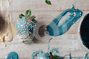 Tasty Blue chocolate dipped strawberry with sugar sprinkles on wood background