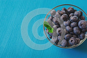 Tasty blueberries with mint on blue background. Blueberries are antioxidant organic superfood.