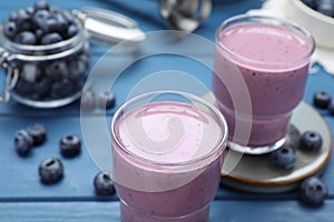 Tasty blueberry smoothie and fresh berries on blue wooden table, closeup