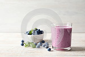 Tasty blueberry smoothie in glass, bowl