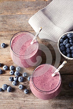 Tasty blueberry smoothie in glasses and berries on wooden table