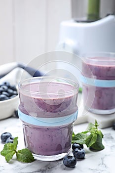 Tasty blueberry smoothie with mint and fresh berries on white marble table, closeup