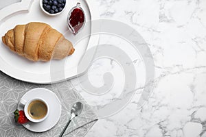 Tasty breakfast with fresh croissant and aromatic coffee on white marble table, flat lay. Space for text