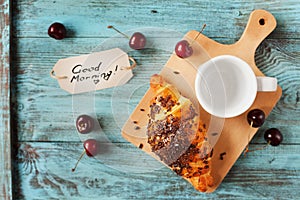 Tasty breakfast with fresh croissant, empty cup of coffee, cherries and notes on a wooden table