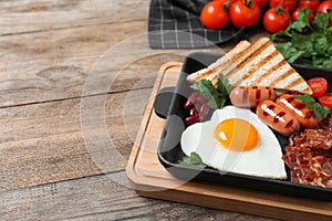 Tasty breakfast with heart shaped fried egg and  sausages on table, closeup