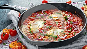 Tasty Breakfast Shakshuka in a Iron Pan. Fried eggs with tomatoes, red, yellow peppers, onion, parsley, Pita bread and