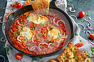 Tasty Breakfast Shakshuka in a Iron Pan. Fried eggs with tomatoes, red, yellow peppers, onion, parsley, Pita bread and