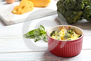 Tasty broccoli casserole in ramekin on white table