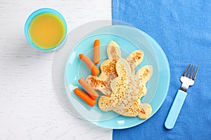 Tasty bunny shaped pancakes served with carrots and juice on white wooden table. Creative idea for kids breakfast