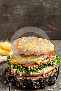 Tasty burger with chicken cutlet and pineapple, fast food and unhealthy eating concept. vertical image