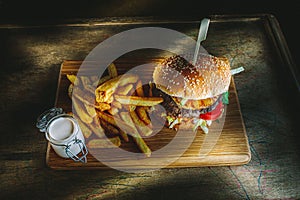 Tasty burger and french fries on wooden board