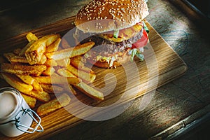 Tasty burger and french fries on wooden board