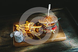 Tasty burger and french fries on wooden board