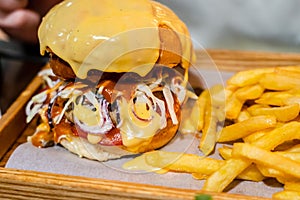 Tasty burger and french fries on wooden desk