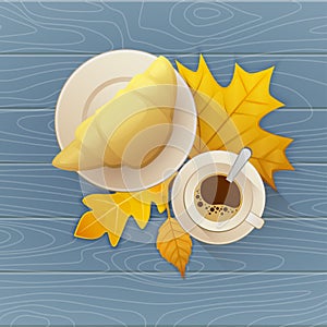 Tasty buttery croissant and cup of hot coffee on old wooden table with autumn leaves