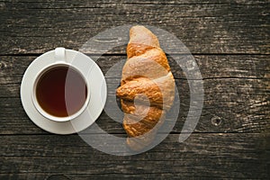 Tasty buttery croissant and cup of tea.