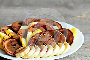 Tasty cacao pancakes. Baked cacao pancakes drizzled with caramel, fresh sliced bananas and apples on a plate