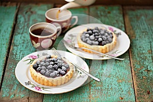 Tasty cakes with fresh wild blackberries and icing sugar with tw