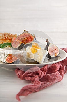 Tasty camembert with fresh figs and honey with honeycombs, decorated on a white wood plate background