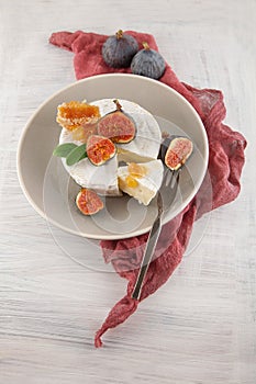 Tasty camembert with fresh figs and honey with honeycombs, decorated on a white wood plate background