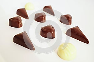 Tasty candies from dark and white chocolate isolated on white background macro. Candy from black chocolate is heart-shaped