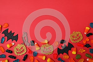 Tasty candies and Halloween decorations on red background, flat lay. Space for text