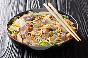 Tasty Cellophane noodles with fried pork belly, shiitake and napa cabbage in soy sauce close-up in a plate. Horizontal
