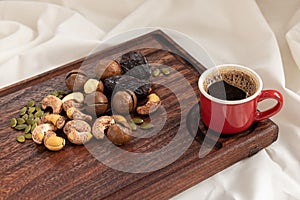 A tasty charcuterie board full of various nuts and coffee for breakfast.