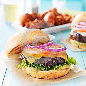 Tasty cheeseburgers with wings and beer