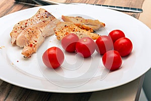 Tasty cherry tomatoes with fish on a white plate