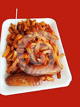 Tasty Chips masala and Sausage on a white disposable plate with orange backgound and a toothpick