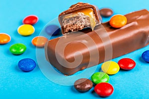 Tasty chocolate bar with toffee and colorful glazed round candies