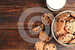 Tasty chocolate chip cookies and glass of milk on wooden table, top view