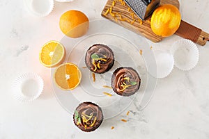 Tasty chocolate cupcakes with orange fruit on light table