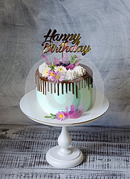 Tasty chocolate drip cake decorated with zephyr and flowers