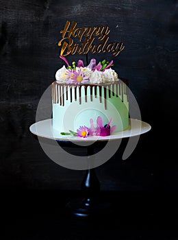 Tasty chocolate drip cake decorated with zephyr and flowers