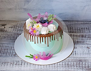 Tasty chocolate drip cake decorated with zephyr and flowers