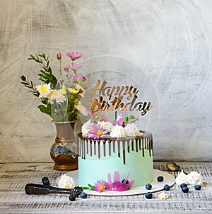 Tasty chocolate drip cake decorated with zephyr and flowers