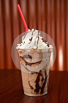 A tasty Chocolate Milkshake with chocolate syrup drizzel and whip cream.