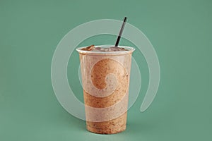Tasty chocolate milkshake in plastic cup on green background photo