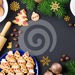 Tasty Christmas cookies, Christmas tree, decorations on black background. Christmas cooking concept. Top view