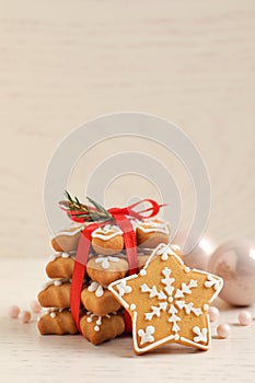 Tasty Christmas cookies tied with red ribbon and festive decor on beige wooden table, space for text