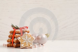 Tasty Christmas cookies tied with red ribbon near festive decor on beige wooden table, space for text