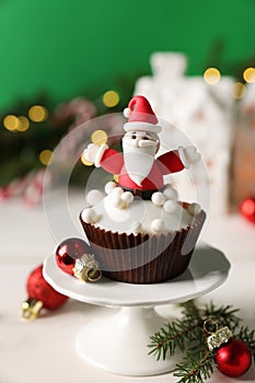 Tasty Christmas cupcake with Santa Claus figure on white table