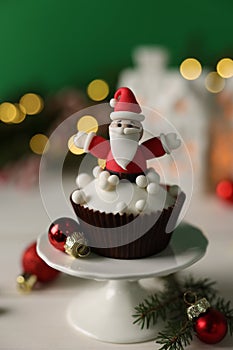 Tasty Christmas cupcake with Santa Claus figure on white table