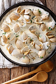 Tasty clams in a creamy sauce with garlic and greens close-up on