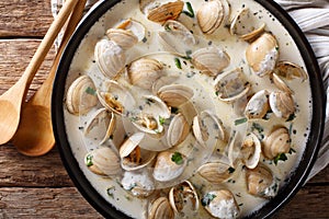 Tasty clams in a creamy sauce with garlic and greens close-up on