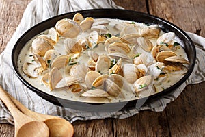 Tasty clams in a creamy sauce with garlic and greens close-up on