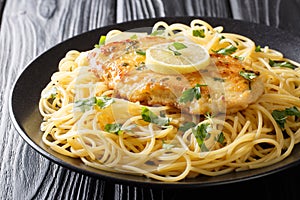 Tasty classic chicken Francaise with spaghetti in lemon wine sauce close-up on a plate. horizontal photo
