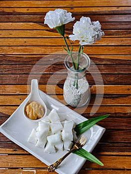 Tasty coconut milk serve with caramel sauce decorated with flower is on wooden table